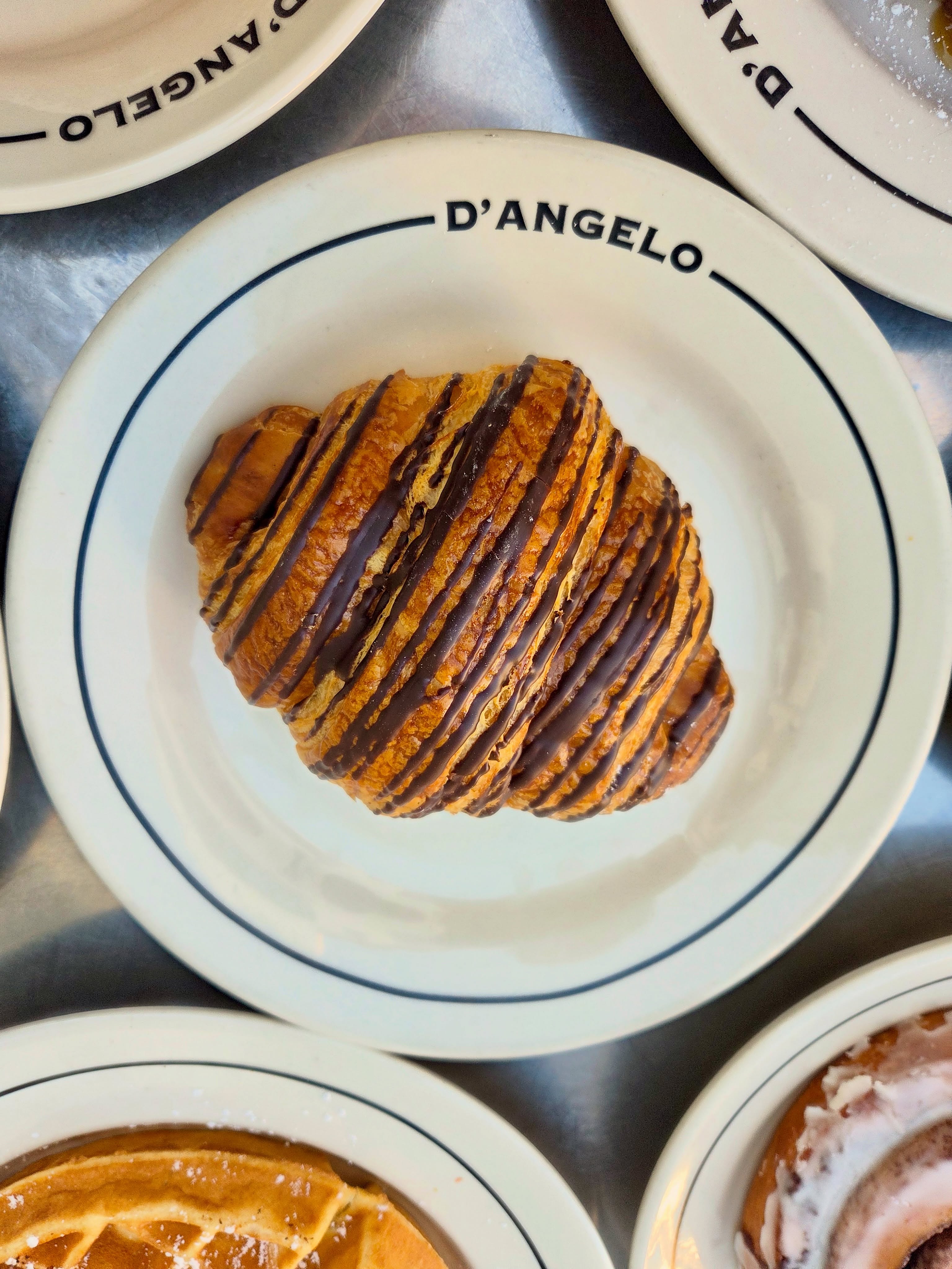 Artisan loaf slice with butter on D'ANGELO signature plate with cappuccino