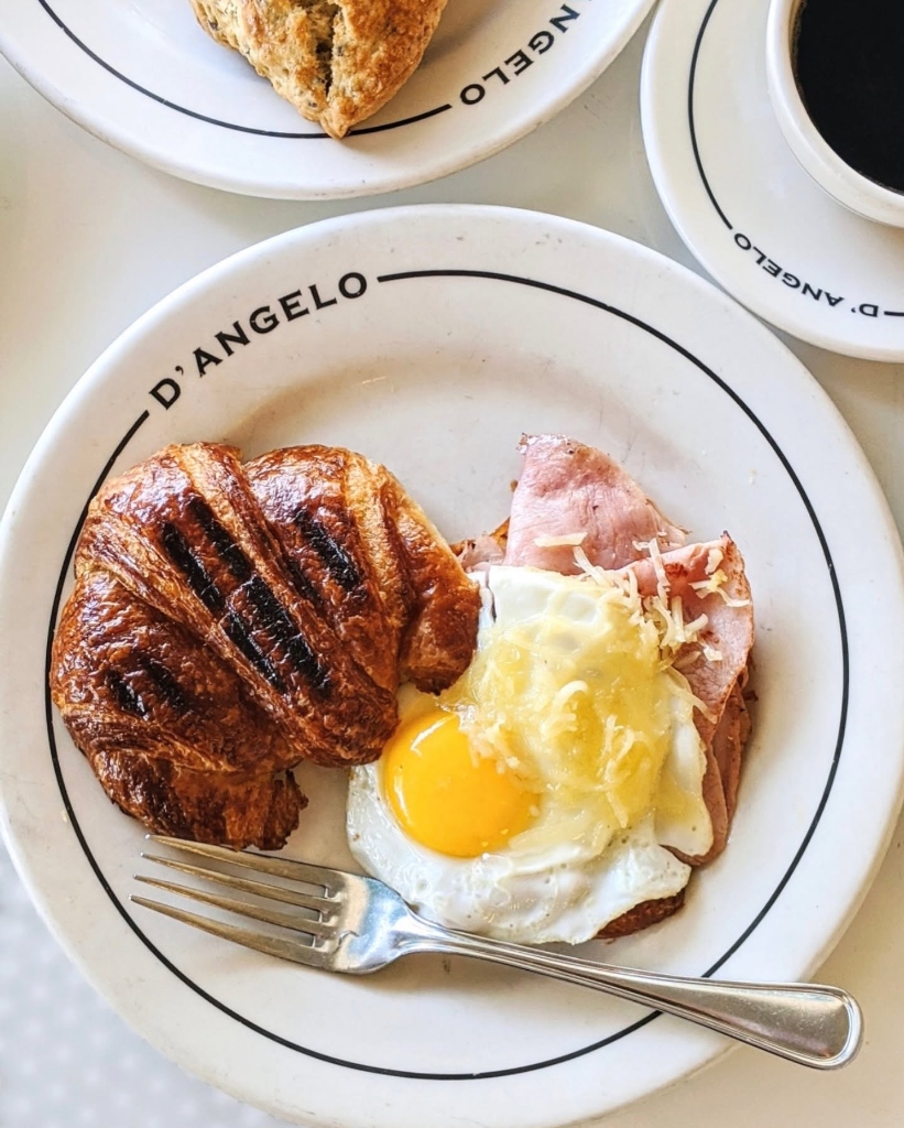 Grilled butter croissant with fried egg, ham & melted cheese with black coffee
